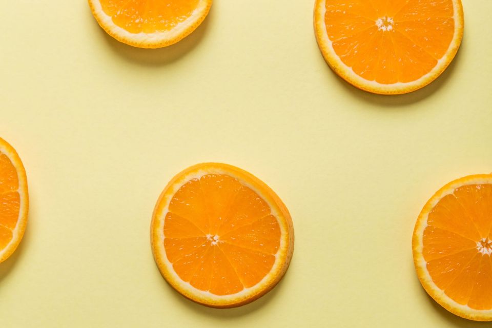 Fatias de laranja dispostas sobre fundo amarelo claro