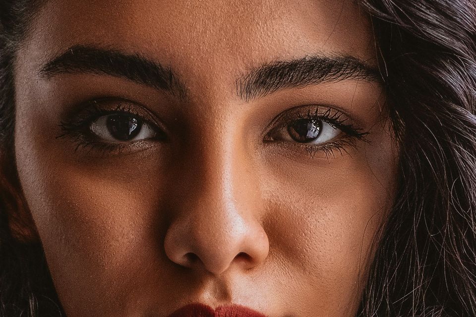 Close do rosto de uma mulher de pele morena sob luz suave