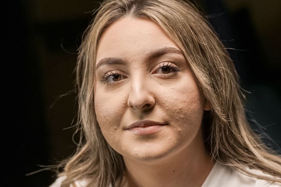 Retrato em close do rosto de uma mulher com pele natural, sem maquiagem pesada, sobre fundo escuro