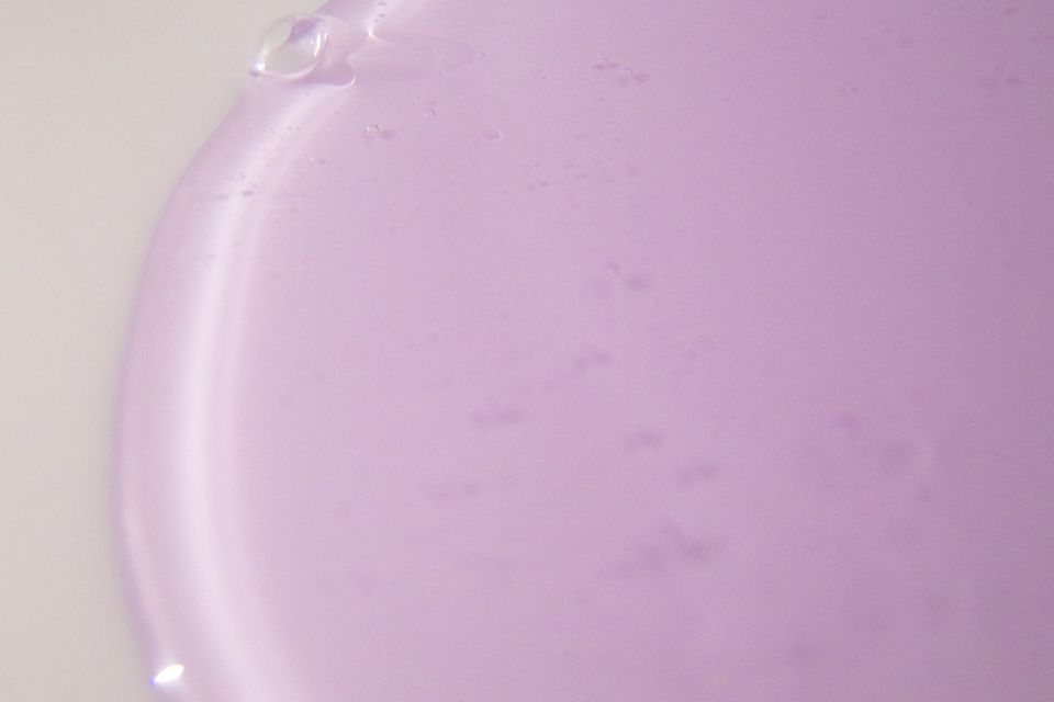 Gel transparente lilás espalhado sobre superfície clara, em close