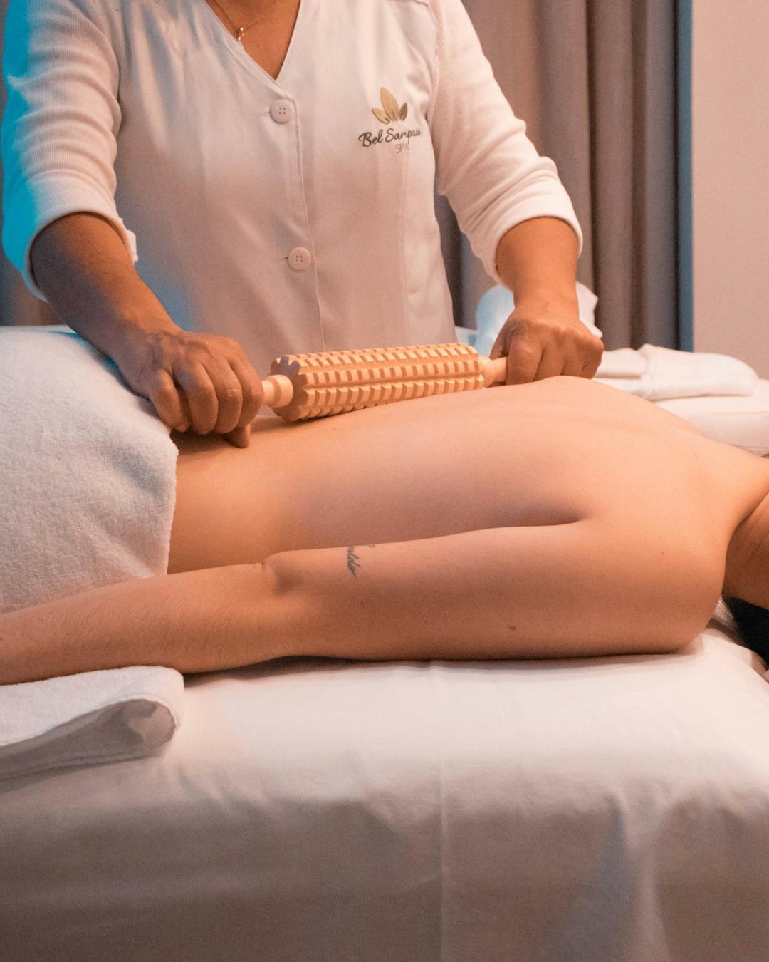 Mulher recebendo massagem nas costas com rolo de madeira